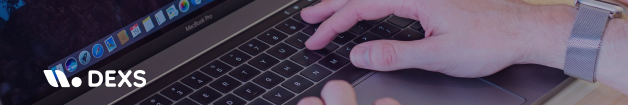 Mano escribiendo en teclado de portátil MacBook con logo de DEXS superpuesto, representando tecnología y soluciones digitales